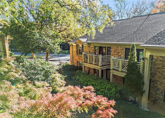 View of a two-story house with a brick exterior and wooden porch railings.