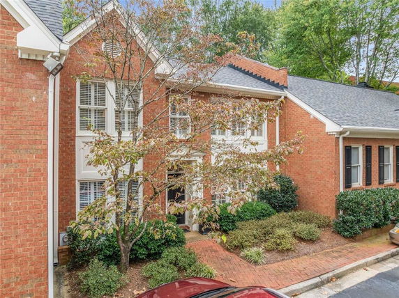 Front view of a two-story brick house with white window frames and a gabled roof.