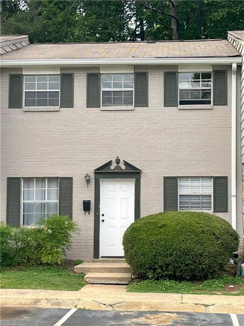 Front view of a two-story house with a white door and green shutters.