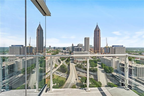 Panoramic view of a cityscape with tall buildings and highways seen from a balcony.