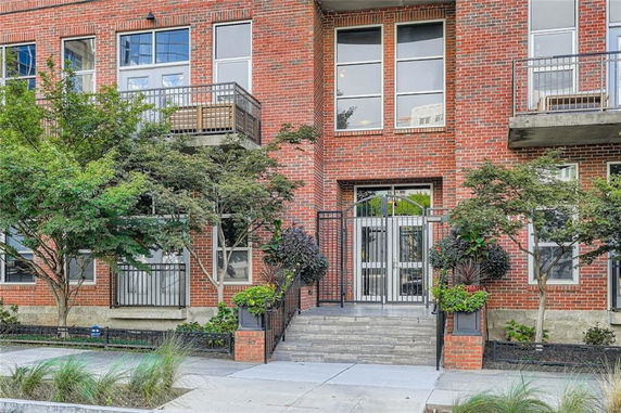 Front view of a brick multi-story building with balconies and large windows.