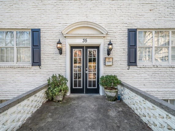 Entrance view of a brick building with double glass doors and black shutters.