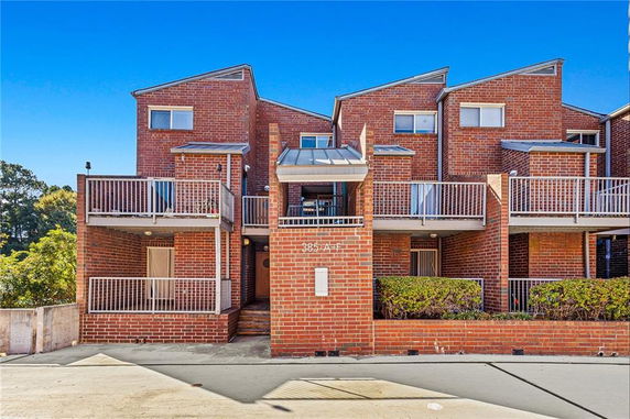Front view of a modern multi-story brick building with balconies.