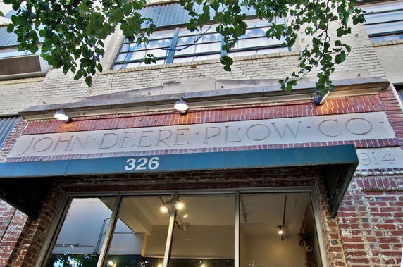 Front view of a brick building with signs for John Deere Plow Co.