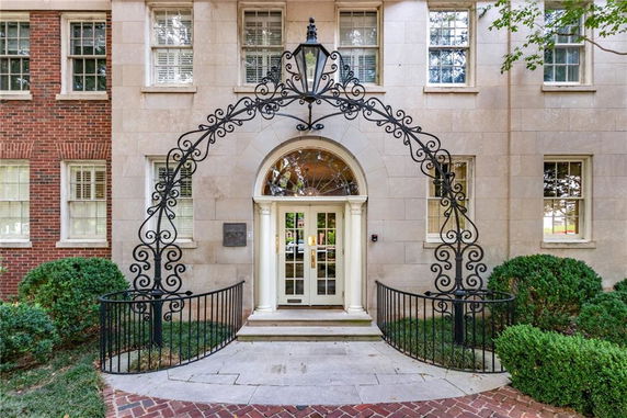 Front view of a building with an ornamental arch above the entrance and symmetrical windows.