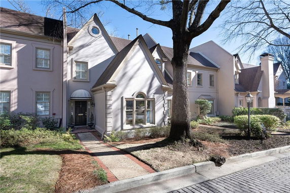 Front view of a multi-story townhouse with a pointed roof and large windows.