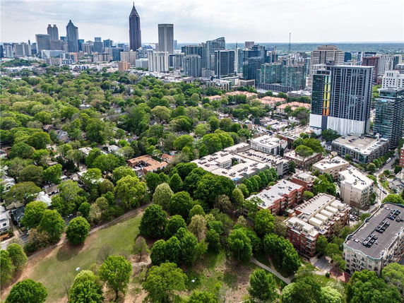 Panoramic view of a city skyline with numerous buildings and surrounding greenery.