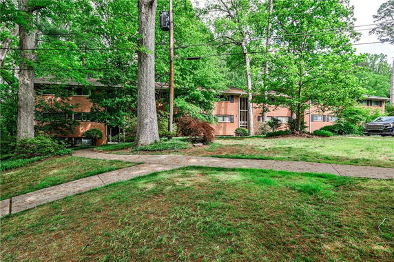 Front view of a multi-story brick building with surrounding trees.