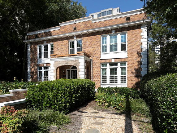 Front view of a two-story brick house with white trim and multiple windows.