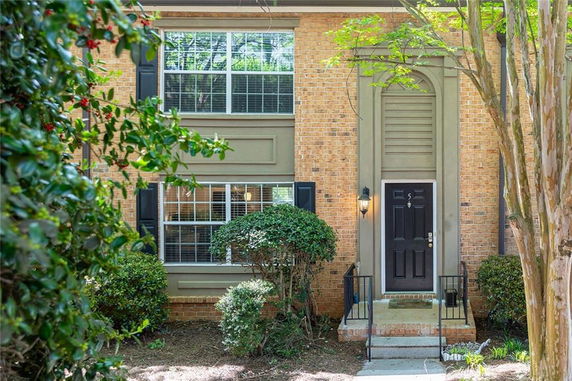 Front view of a two-story brick house with black shutters and a central entrance.