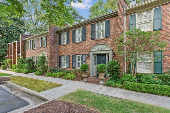 Front view of a brick townhouse with black shutters and a central entrance.