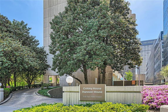 Front view of a multi-story building with large trees and a sign for Colony House Hanover House.