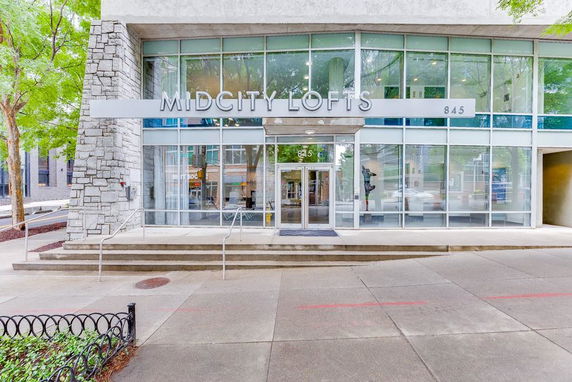 Front view of a building named Midcity Lofts with large glass windows and stone accents.