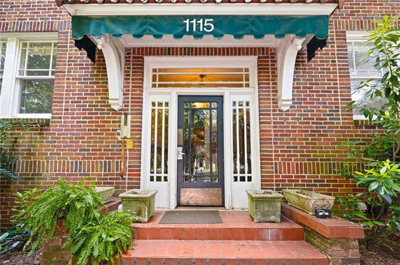 Front view of a brick house entrance with a green awning and glass door.