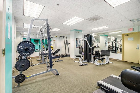 Indoor gym area with various exercise equipment including weights and machines.