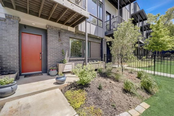 Front view of a multi-story building with a red door and garden area.