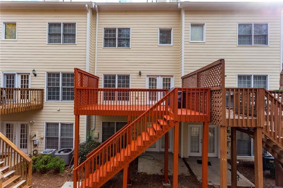 Back view of a multi-story residential building with wooden decks and stairs.