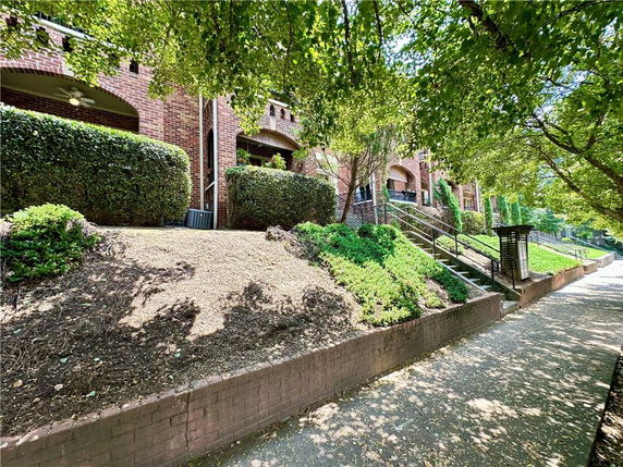 Front view of a multi-story brick building with arched balconies and landscaped surroundings.
