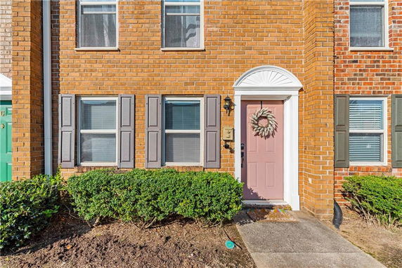 Front view of a brick house with a pink door and decorative wreath.
