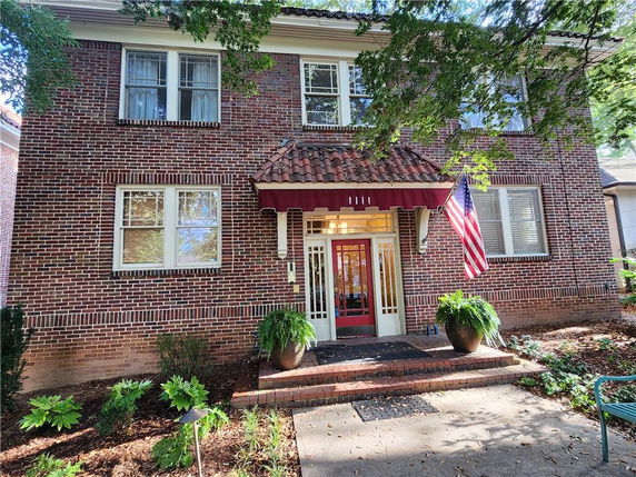 Front view of a two-story brick house with a red canopy over the entrance.