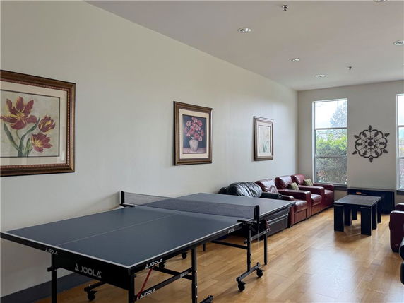 Room with a table tennis setup and several couches along the wall.