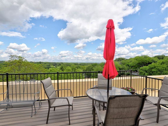 Rooftop area with patio furniture and an umbrella overlooking a scenic view.