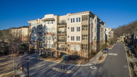 Front view of a multi-story apartment building with balconies and large windows.