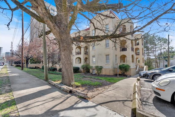 Front view of a multi-story residential building with arched balconies and beige exterior.