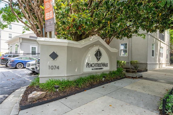 Front view of a condominium entrance with signage and nearby parked cars.