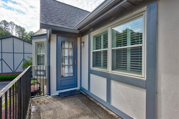 Exterior view of a house with a balcony and a blue door.