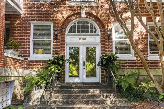 Front view of a brick building entrance with arched windows and a double door.