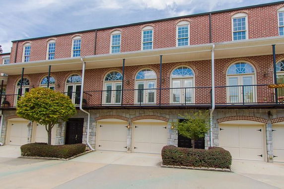 Front view of a multi-story brick building with garages on the ground floor.