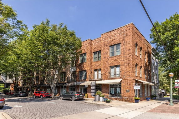Front view of a three-story brick building with retail space on the ground floor.