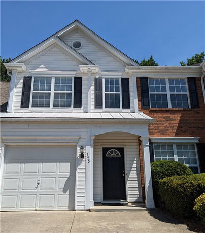 Front view of a two-story house with a garage and dark shutters.