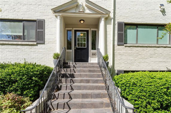 Front view of a house with steps leading to the entrance and columns on either side of the door.