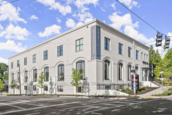 Front view of a multi-story building with large windows and a corner entrance.