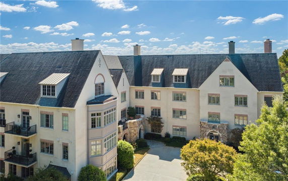 Front view of a multi-story residential building with large windows and a steep roof.