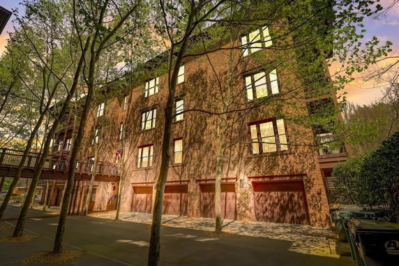 Front view of a multi-story brick building with balconies and trees in front.