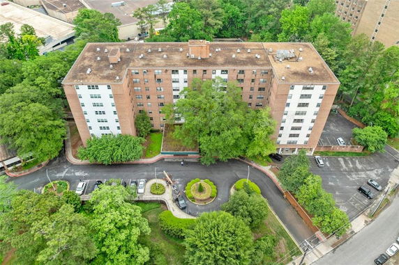 Aerial view of a large brick apartment complex with surrounding trees and parking area.