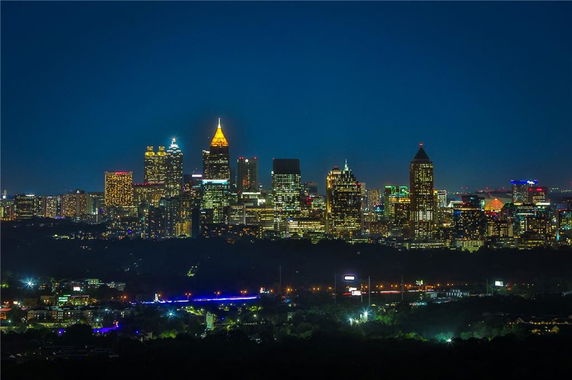 Panoramic view of a city skyline at night with illuminated skyscrapers.