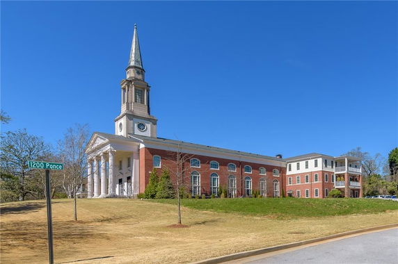 Front view of a large, brick building with a tall steeple and classical columns.