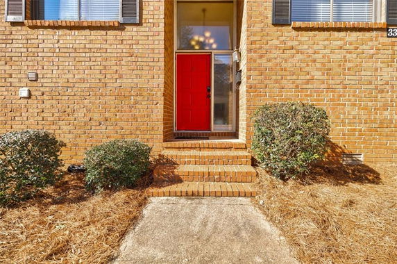 Front view of a brick house with a red front door and steps.