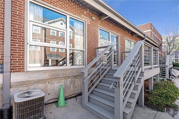 Front view of a brick building with staircase leading to entrance.