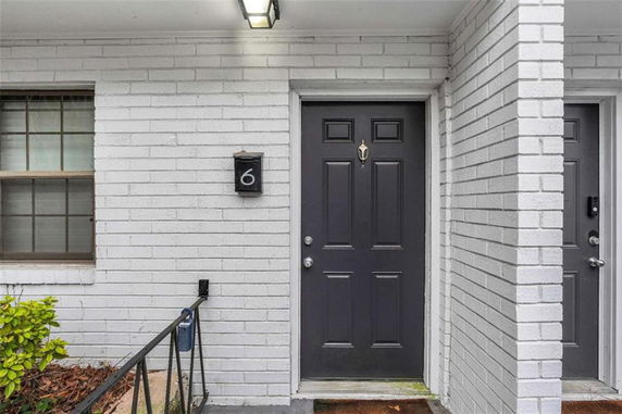 Front view of a building entrance with brick walls and a black door.
