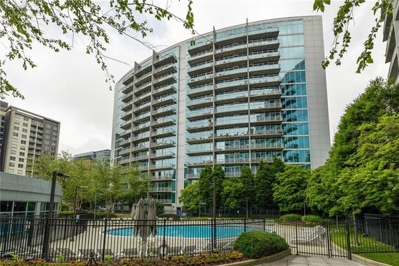 Front view of a multi-story glass apartment building with balconies.