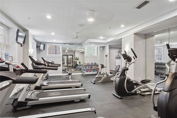 Indoor gym area with treadmills, exercise bikes, and weights.