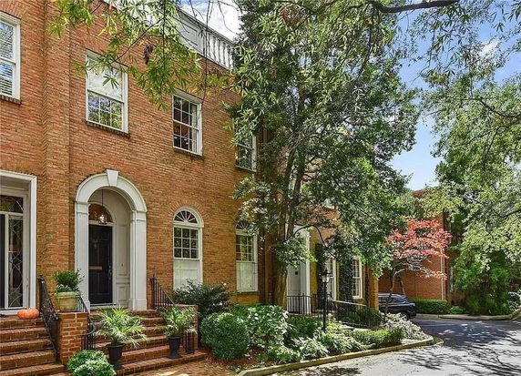 Front view of a brick townhouse with arched entry and windows.