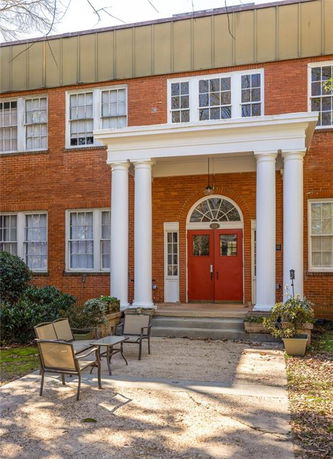 Front view of a two-story brick building with columns and red doors.