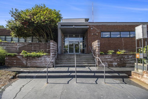 Front view of a brick building with steps leading to the entrance.