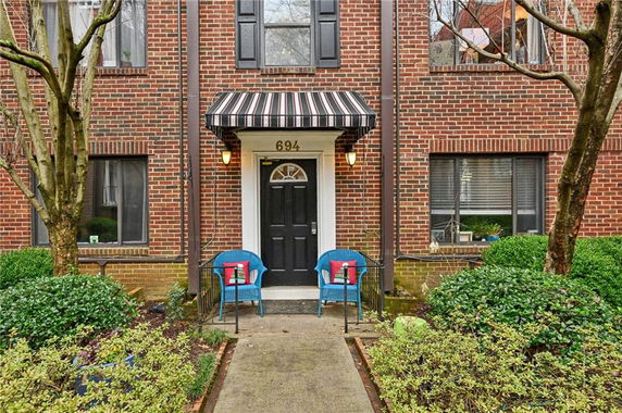 Front view of a brick house with a black door and striped awning.